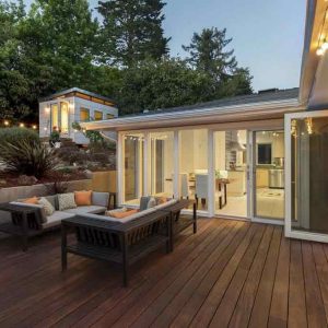 House with a huge deck and backyard furniture. Nice trees in the back of the house